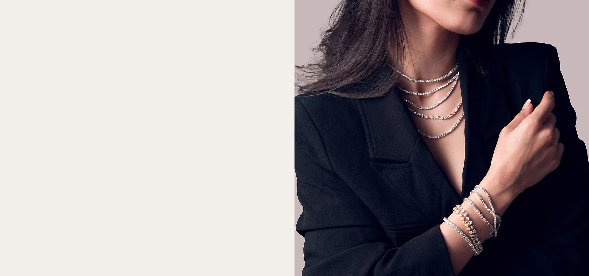 Model wearing layered diamond tennis necklaces and bracelets with a black blazer